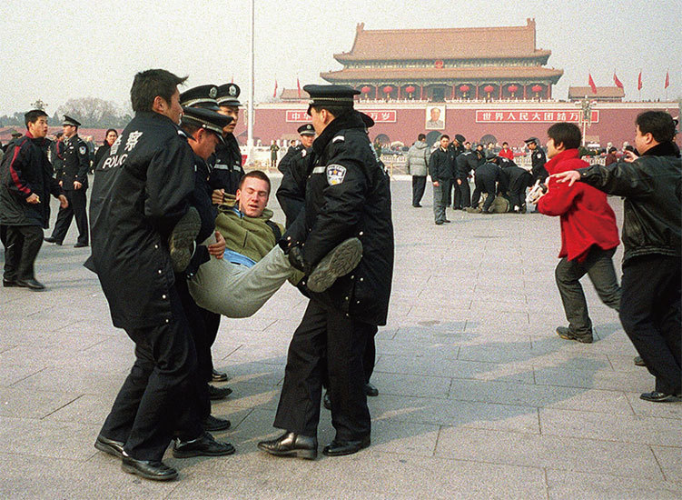 历史资料图:中国警察在北京天安门广场强行带走一名法轮功学员。AFP画面直接记录国家执法力量介入、控制并带离法轮功学员;用于呈现迫害责任链中的公安抓捕环节,不作为2026年9月个案现场|来源:AFP/新纪元周刊转载