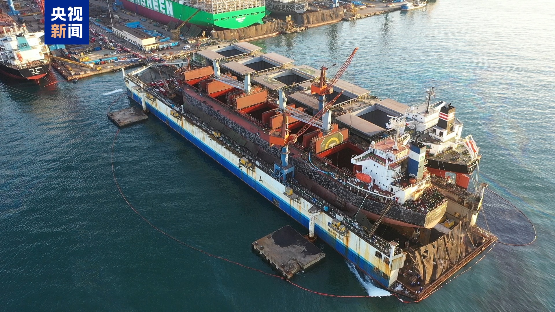 青岛北海造船货轮火灾事故涉事船舶航拍画面,可见船体、船坞及周边救援区域|来源:央视新闻客户端/正义网