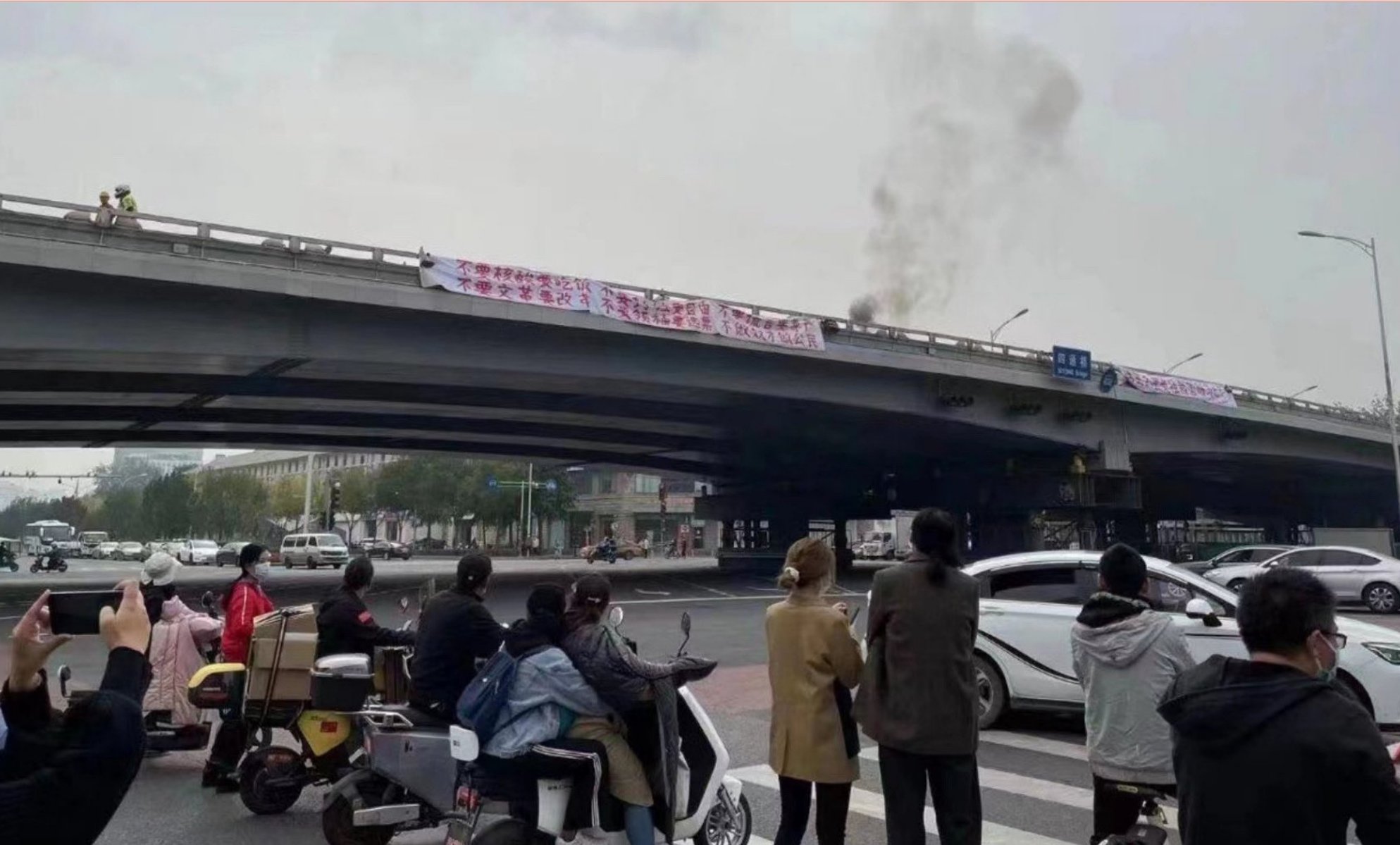 2022年10月13日四通桥现场，从另一角度拍摄的白底红字横幅及桥边浓烟｜来源：西雅图中文电台／2022年10月14日刊载