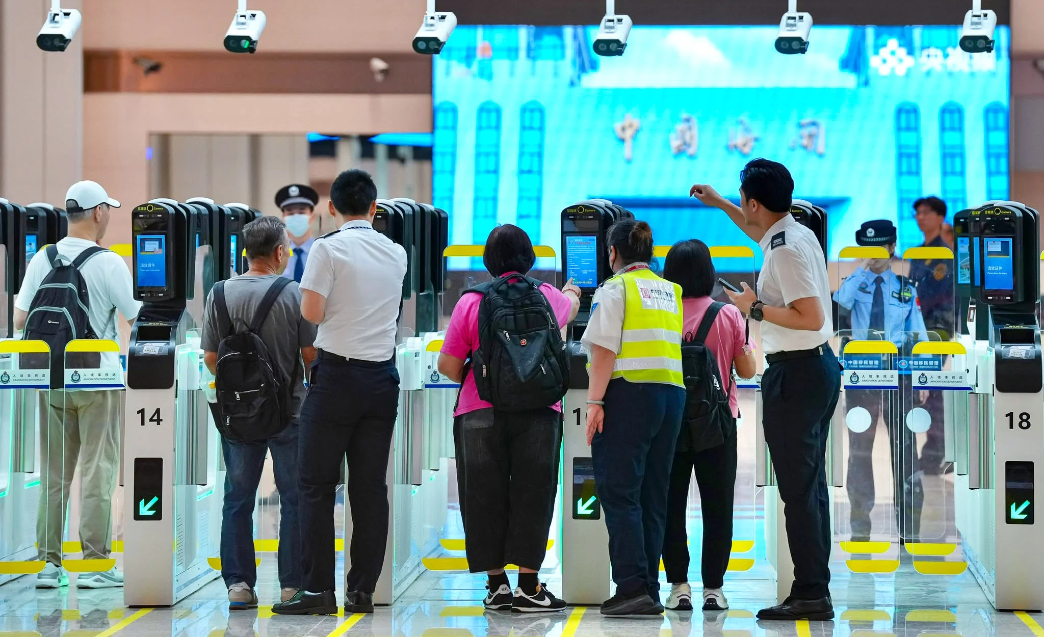 2026年10月12日新皇岗口岸启用首日，旅客与工作人员在合作查验自动闸机区域。不同于封面车辆排队照片｜来源：南华早报／Karma Lo